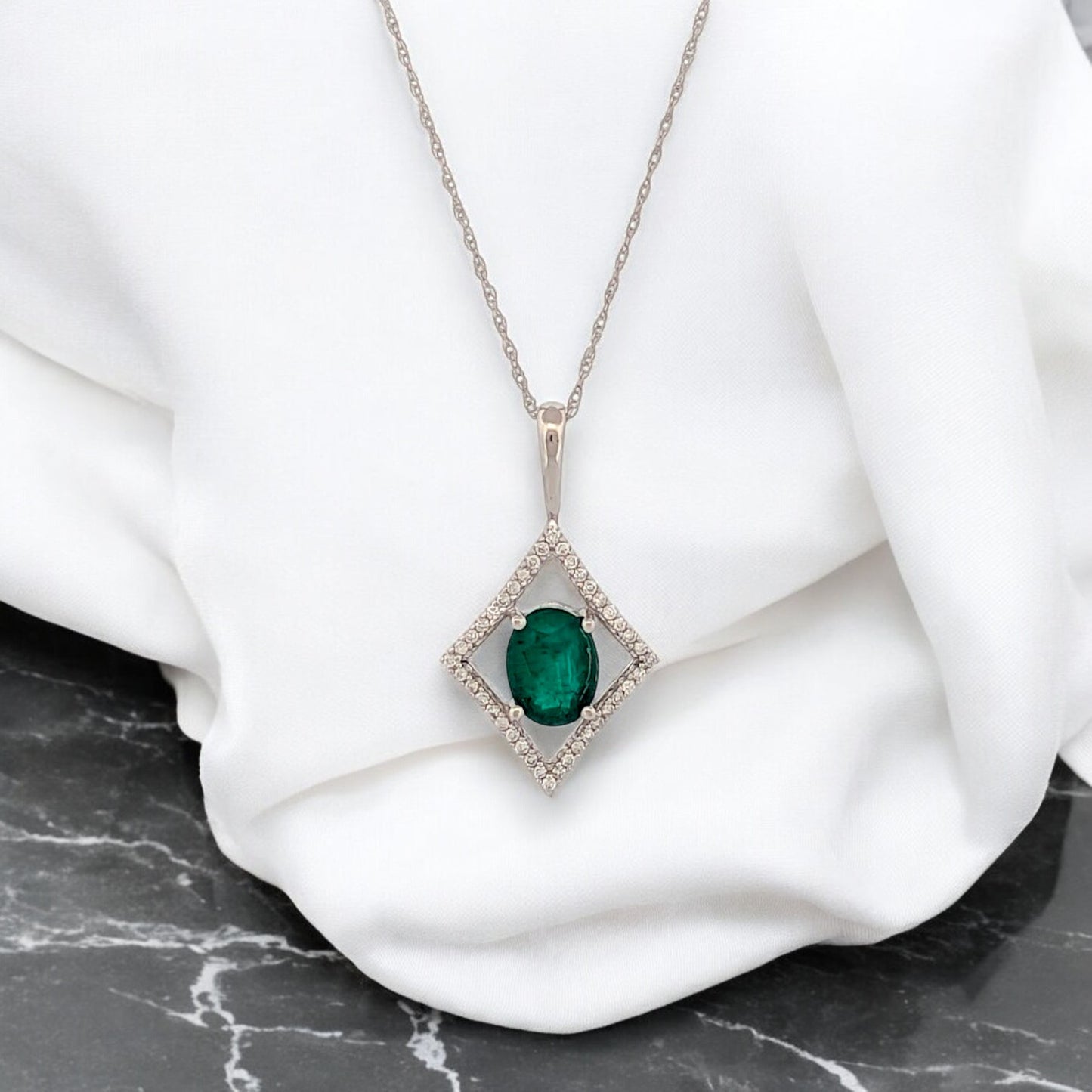 14k white gold necklace with 1.10 ct emerald center stone and .15 ctw diamond pendant