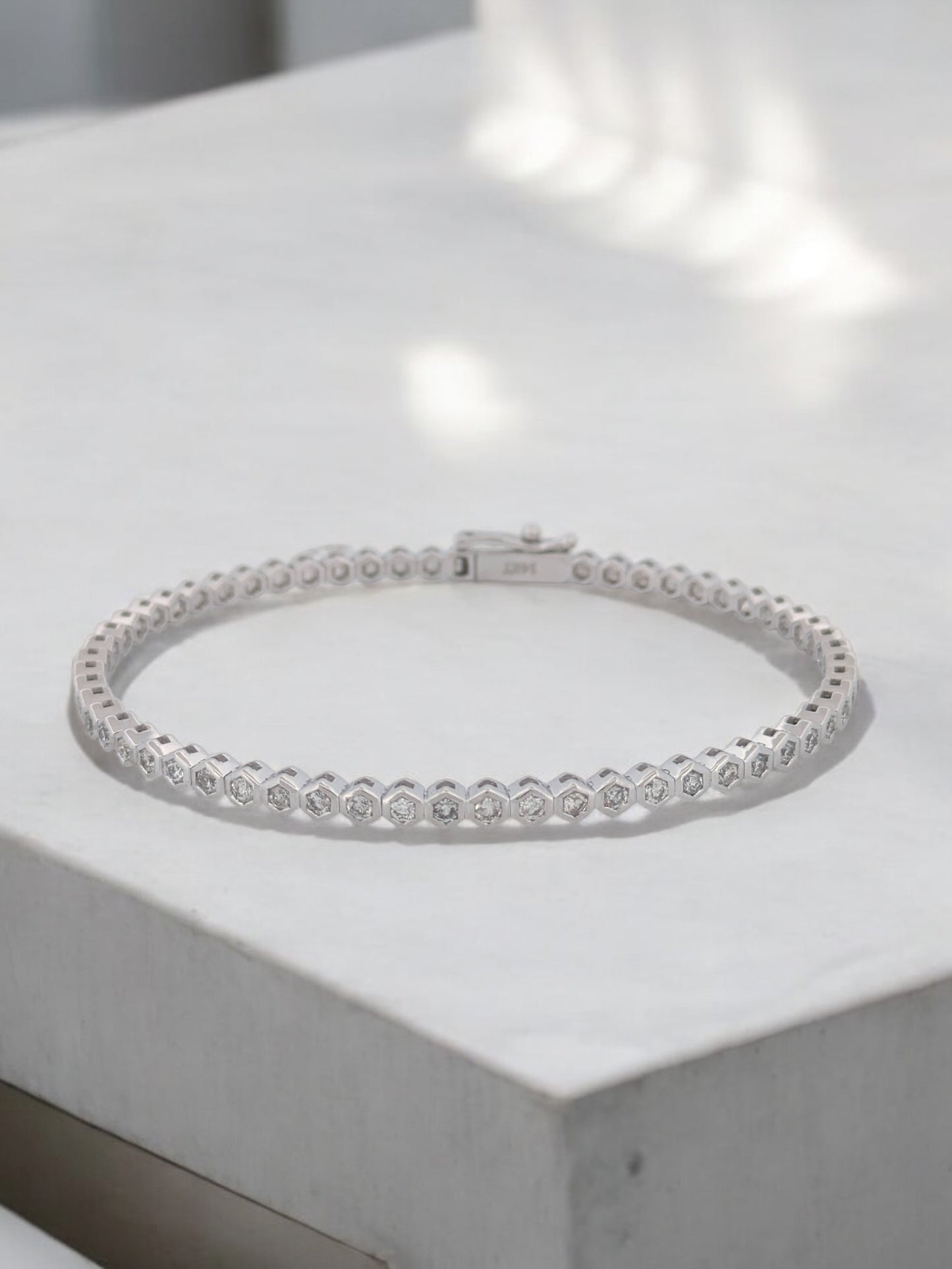 14k white gold bangle bracelet with bezel-set diamonds in a connected hexagon design.